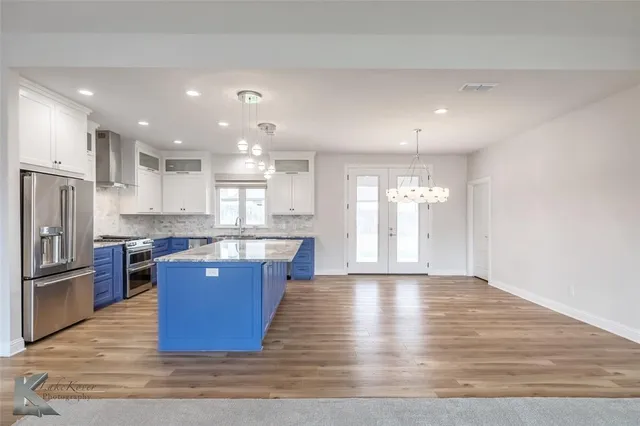 a large kitchen with stainless steel appliances granite countertop a large counter top a stove and a refrigerator