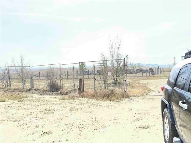 a view of a dry yard with wooden fence
