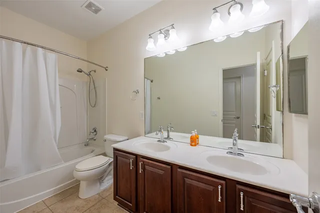 a bathroom with a double vanity sink toilet mirror and shower