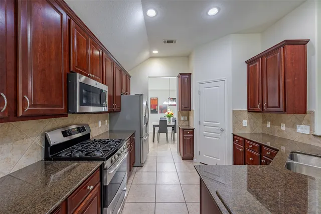 a kitchen with stainless steel appliances granite countertop wooden cabinets a stove a sink and a refrigerator