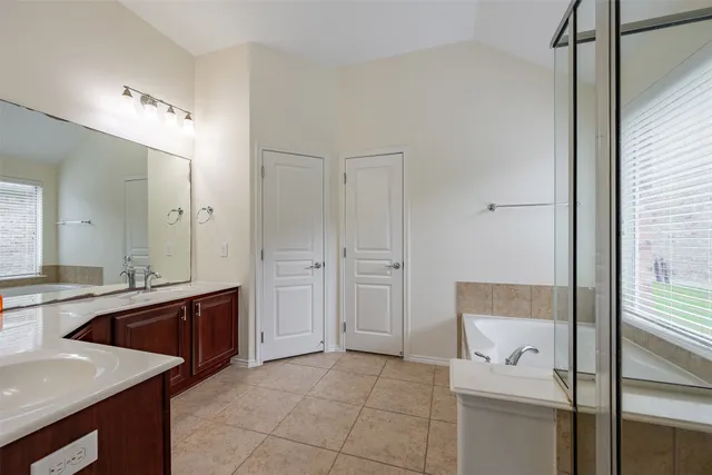 a spacious bathroom with a tub sink shower and mirror