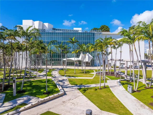 a view of a swimming pool with a lawn chairs and palm trees