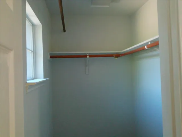 an empty room with wooden floor cabinet and windows