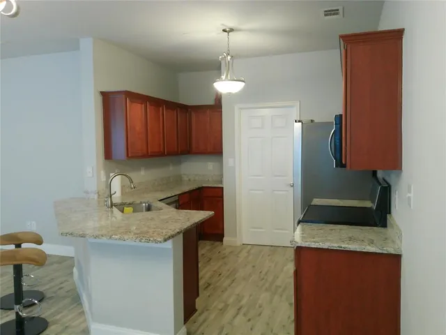 a kitchen with granite countertop kitchen island stainless steel appliances a sink stove and refrigerator