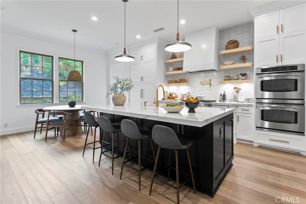 3 Adele Street Ladera Ranch, CA 92694 - Photo 12 of 34 a kitchen with stainless steel appliances granite countertop a stove a refrigerator a kitchen island a dining table and chairs with wooden floor