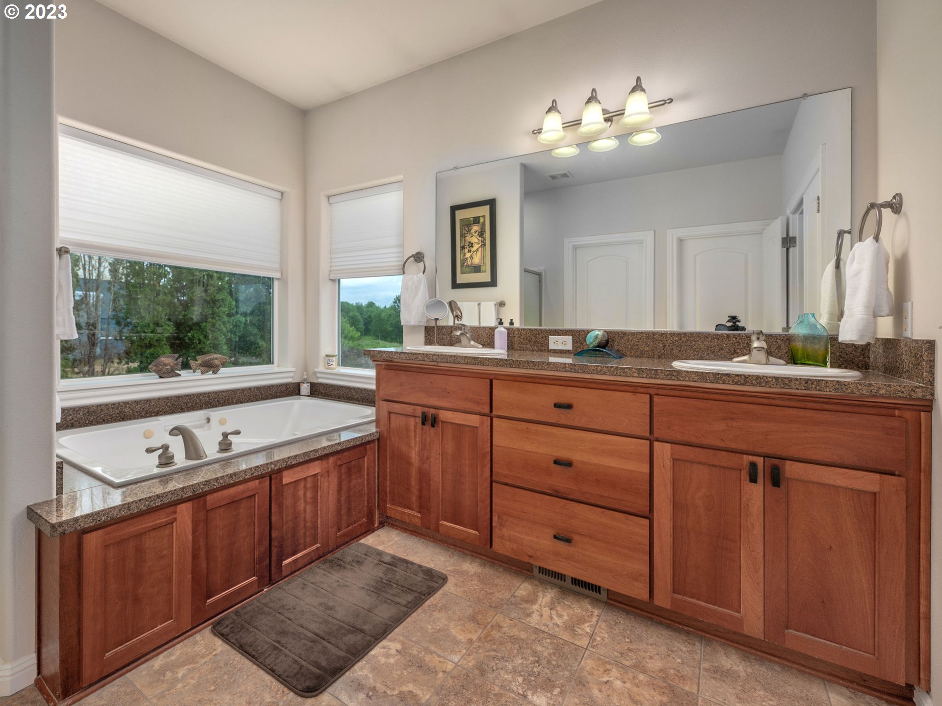 56470 Hazen Road Warren, OR 97053 - Photo 23 of 39 a spacious bathroom with a granite countertop sink and a large mirror