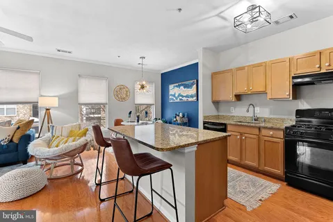 a open kitchen with stainless steel appliances granite countertop a stove top oven a sink a dining table and chairs with wooden floor