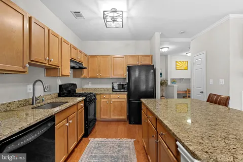 a kitchen with stainless steel appliances granite countertop a sink stove refrigerator and cabinets