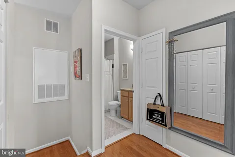 a view of a hallway with bathroom and wooden floor