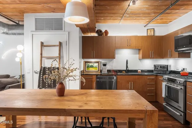 a kitchen with stainless steel appliances granite countertop a stove refrigerator and wooden cabinets