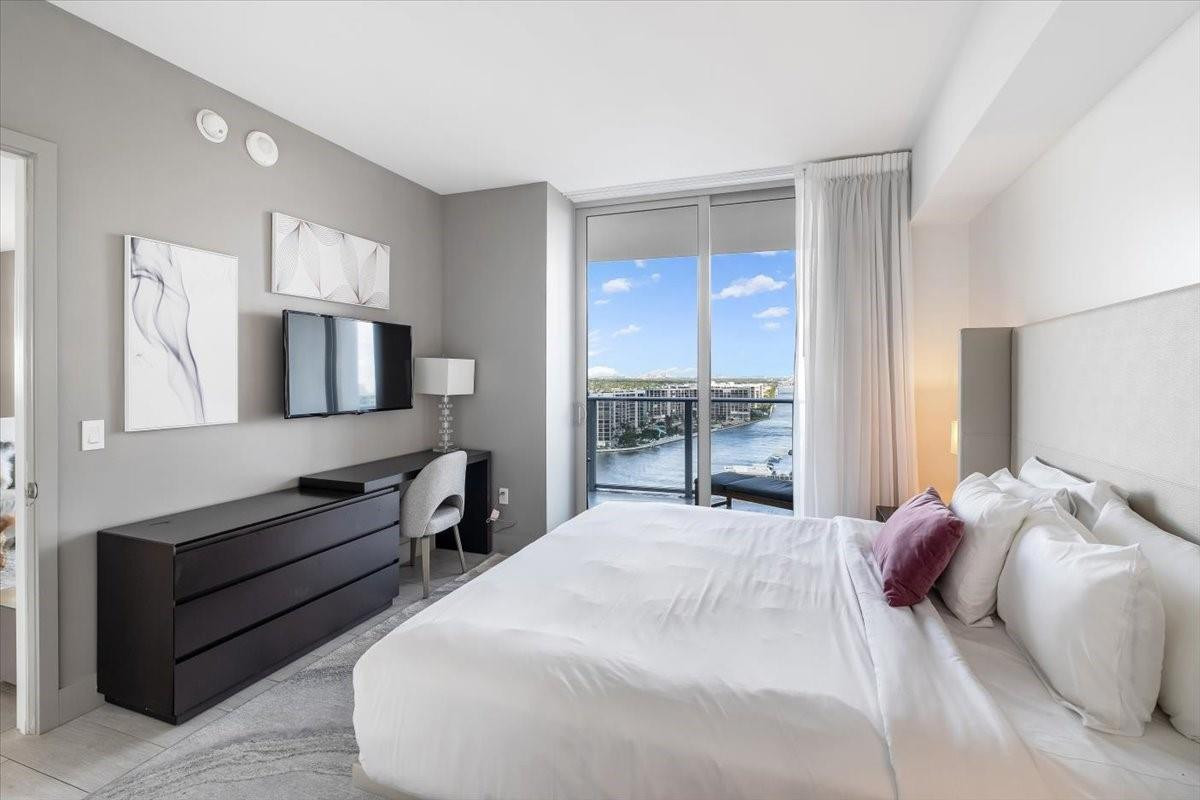 4010 South Ocean Drive, Unit R1102 Hollywood, FL 33019 - Photo 22 of 47 a bedroom with a large bed and a flat tv screen on dresser