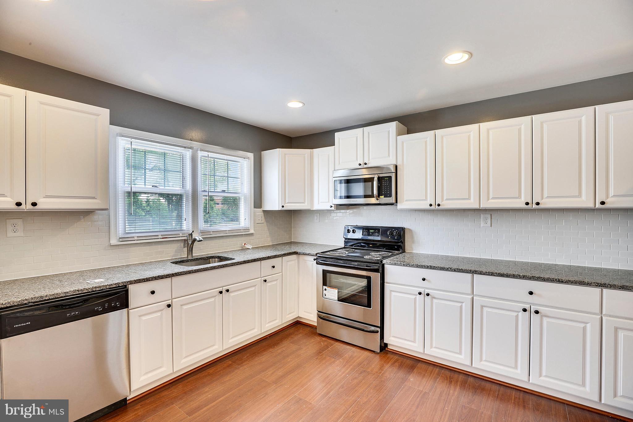 1718 Newcastle Road Baltimore, MD 21244 - Photo 4 of 9 a kitchen with granite countertop white cabinets and white appliances