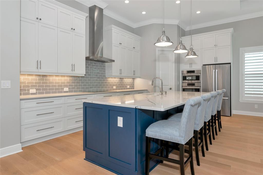 16620 Collingtree Crossing Lakewood Ranch, FL 34202 - Photo 6 of 48 a kitchen with stainless steel appliances kitchen island granite countertop a table chairs in it and wooden floors