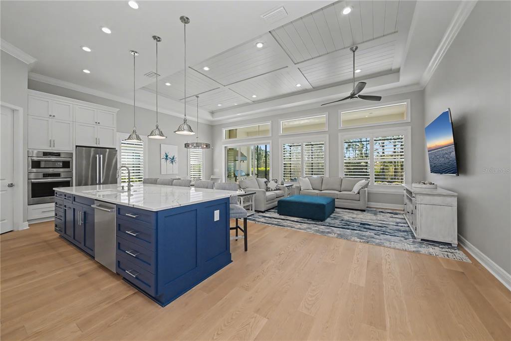 16620 Collingtree Crossing Lakewood Ranch, FL 34202 - Photo 9 of 48 a large living room with stainless steel appliances granite countertop a couch and a flat screen tv