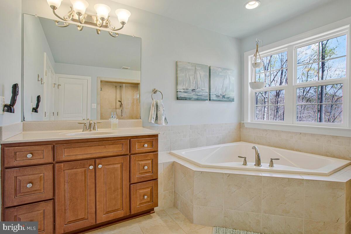 54 Simmons Ridge Road Prince Frederick, MD 20678 - Photo 36 of 55 a spacious bathroom with a tub a double vanity sink a window and a mirror