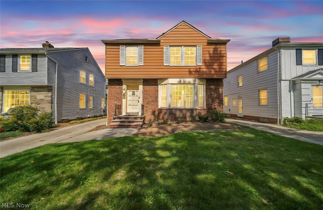 Colonial home with brick siding and a front lawn