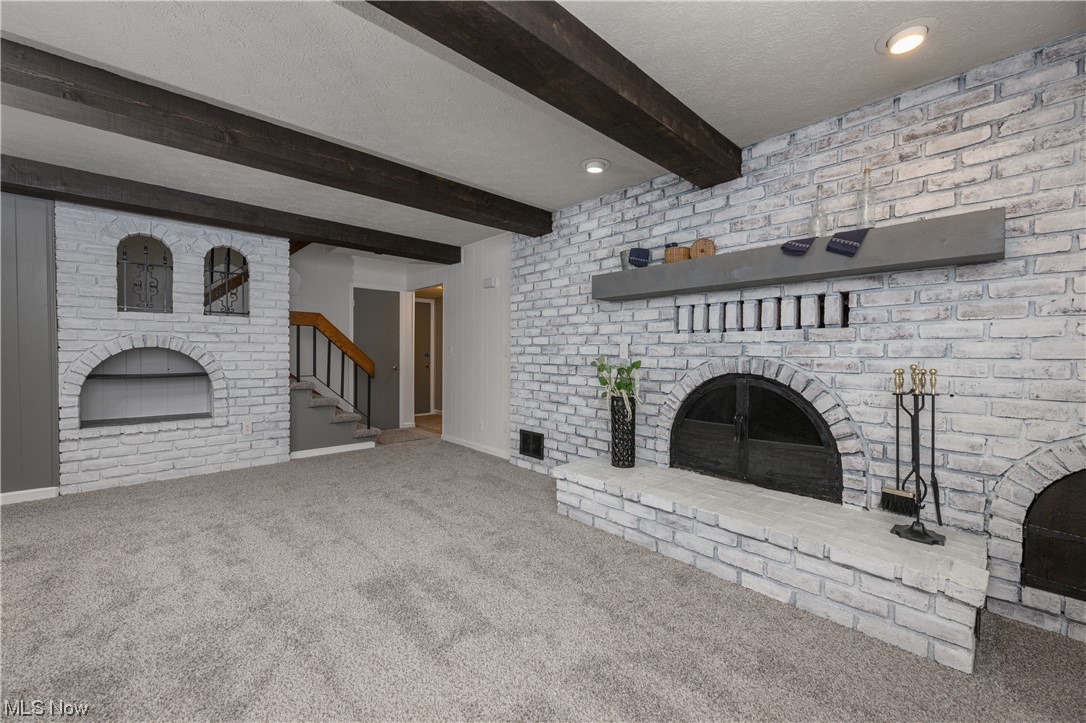 279 South Messner Road New Franklin, OH 44319 - Photo 22 of 30 Unfurnished living room with carpet floors, beam ceiling, a fireplace, and a textured ceiling