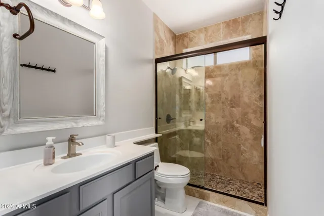 a bathroom with a granite countertop sink mirror vanity and toilet