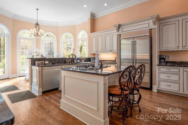 a kitchen with stainless steel appliances granite countertop a stove a sink dishwasher and a refrigerator with wooden floor