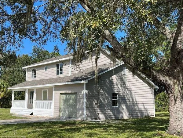 a front view of a house with a large tree