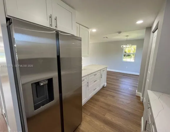 a kitchen with stainless steel appliances a refrigerator and a hard wood floor