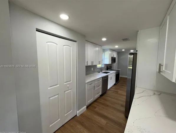 a large kitchen with a lot of counter space and wooden floor
