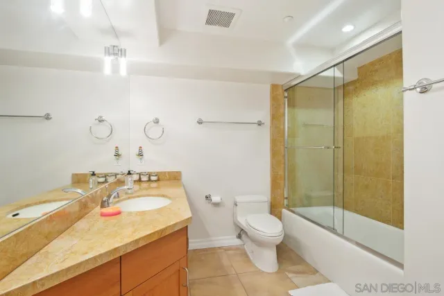 a bathroom with a granite countertop sink mirror vanity and toilet