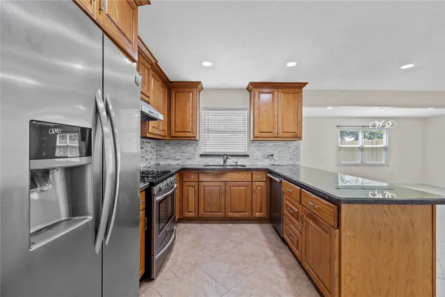 a kitchen with stainless steel appliances granite countertop a refrigerator and a sink