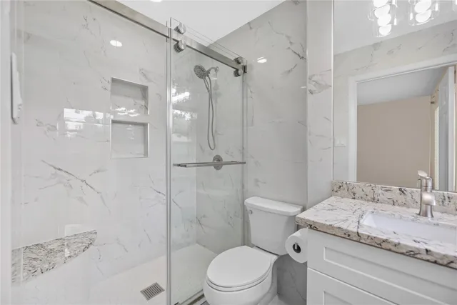 a bathroom with a granite countertop sink toilet a mirror and shower
