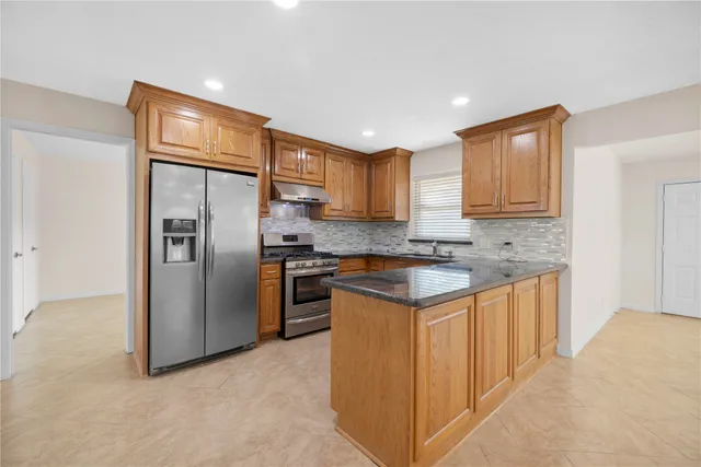 a kitchen with stainless steel appliances granite countertop a refrigerator and a stove top oven