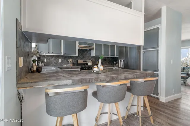 a kitchen with stainless steel appliances granite countertop a table chairs sink and cabinets