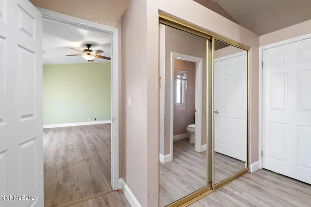 a view of a hallway with wooden floor and a bathroom