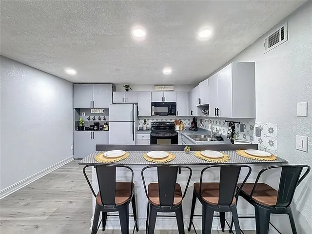 a kitchen with stainless steel appliances kitchen island granite countertop a refrigerator and a sink