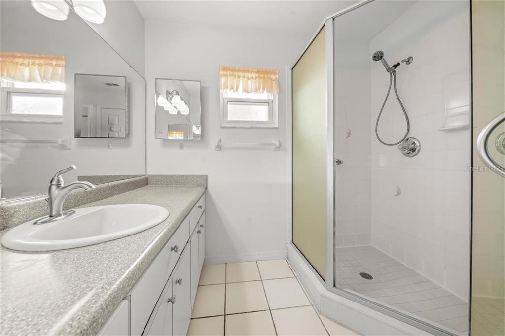 6145 Southwest 100th Loop Ocala, FL 34476 - Photo 36 of 54 a bathroom with a granite countertop sink a mirror and a shower