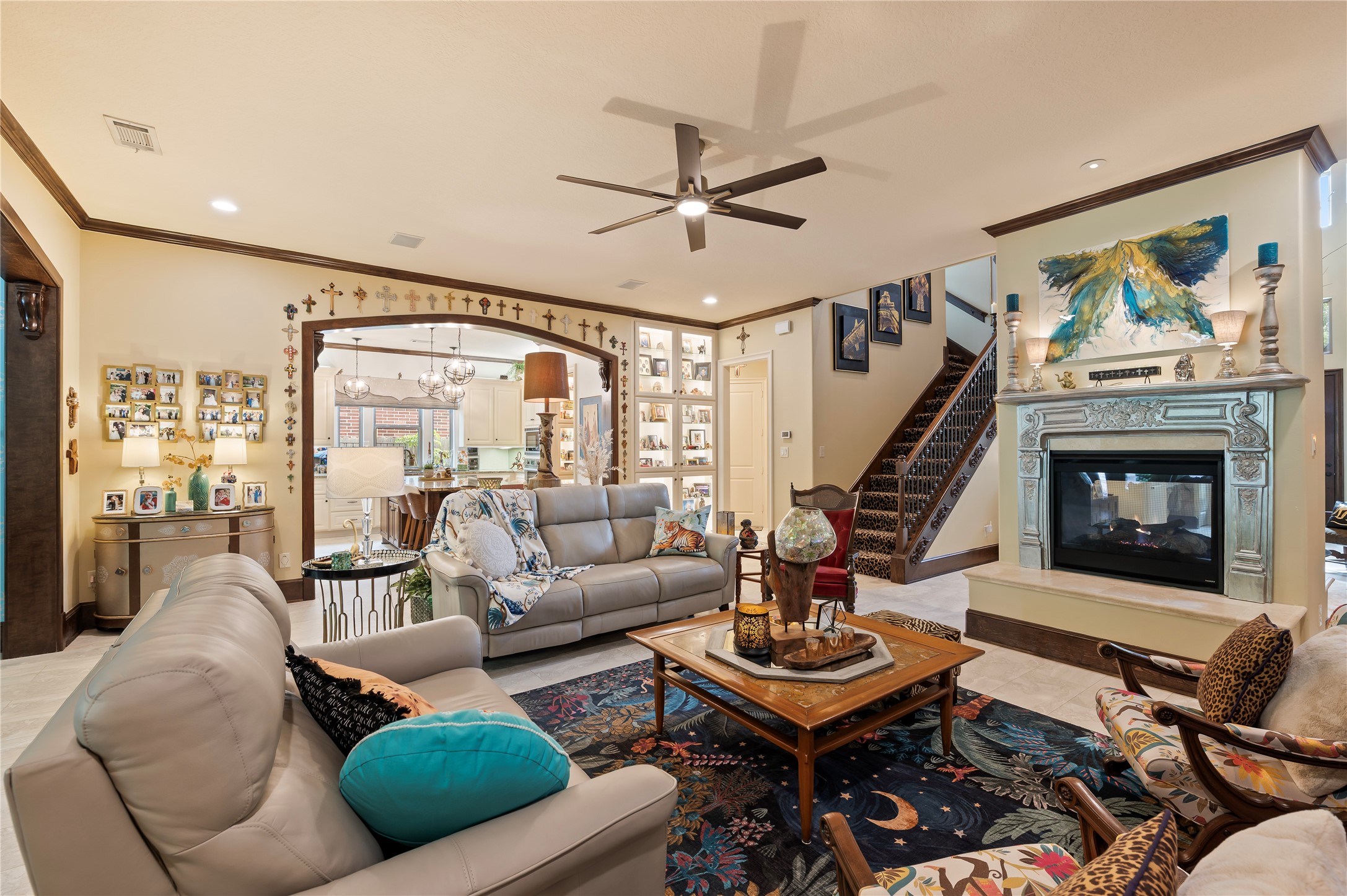 2201 Water Way Seabrook, TX 77586 - Photo 11 of 48 This inviting living room features comfortable seating, a decorative 2-sided fireplace, and a ceiling fan. The open layout reveals a glimpse into the kitchen, and the staircase that leads to the upper level, enhancing the space's functionality and style.