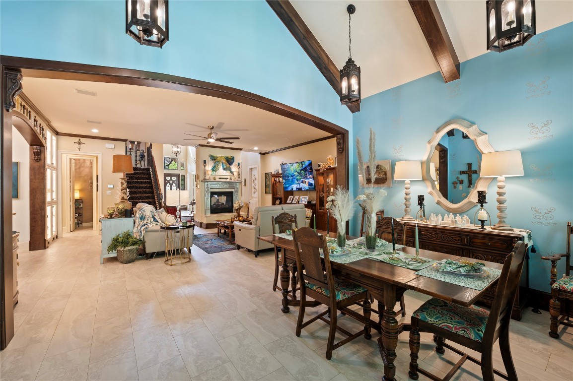 2201 Water Way Seabrook, TX 77586 - Photo 14 of 48 This inviting dining space features a high vaulted ceiling with exposed beams and elegant pendant lighting. The open layout showcases the living area with a fireplace, adjacent to a dining space with ample room for entertaining. The walls are painted a serene blue, adding a touch of warmth and charm to the room.