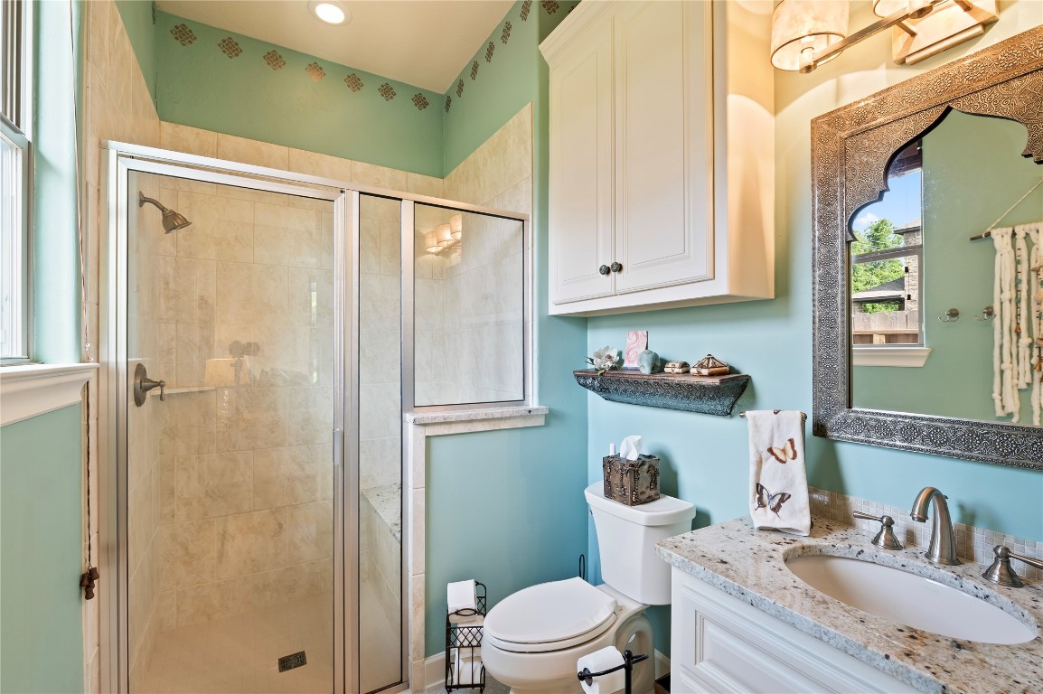 2201 Water Way Seabrook, TX 77586 - Photo 17 of 48 This bathroom features a modern glass-enclosed shower, elegant granite countertop with a stylish sink, and ample storage with cabinets and a decorative shelf. The soothing color palette adds a relaxing touch.