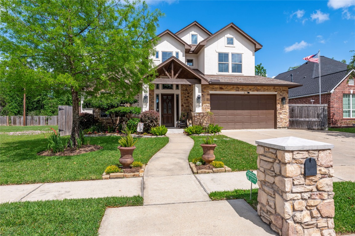 2201 Water Way Seabrook, TX 77586 - Photo 2 of 48 This photo showcases a beautiful two-story home with a stone and stucco facade, featuring a welcoming entryway and a two-car garage. The front yard is well-maintained, with lush greenery and a paved walkway leading to the entrance.