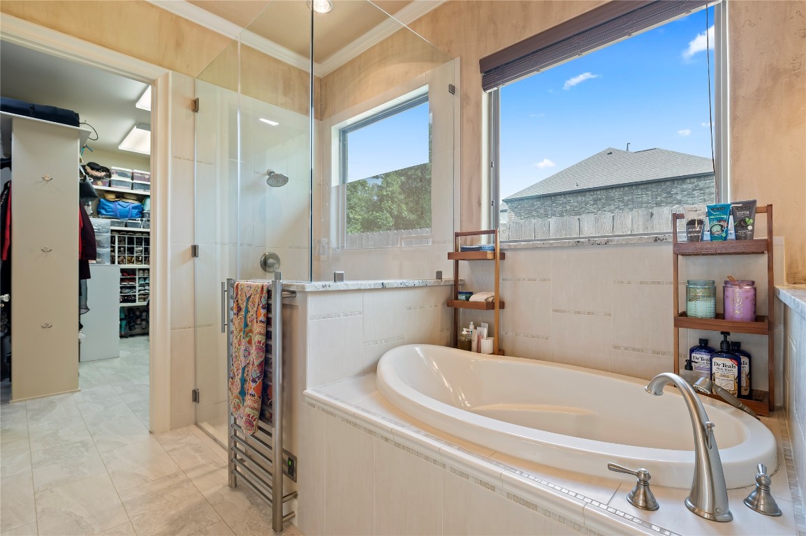 2201 Water Way Seabrook, TX 77586 - Photo 21 of 48 This photo showcases a modern bathroom featuring a spacious soaking tub, a glass-enclosed shower, and a large window offering natural light. Adjacent is a walk-in closet with ample storage space.