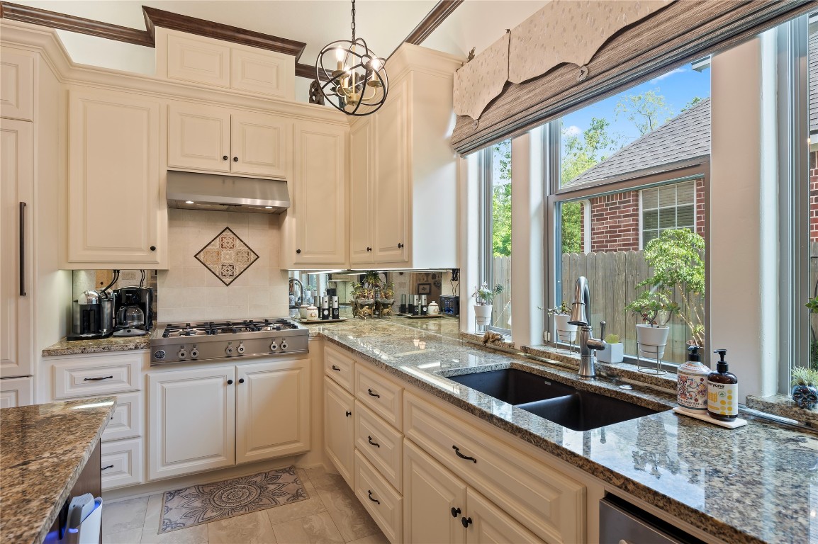 2201 Water Way Seabrook, TX 77586 - Photo 24 of 48 This kitchen features elegant granite countertops, a stainless steel gas stove, and under-cabinet lighting. Large windows provide plenty of natural light, and the ample cabinetry offers generous storage. A modern pendant light adds a stylish touch.