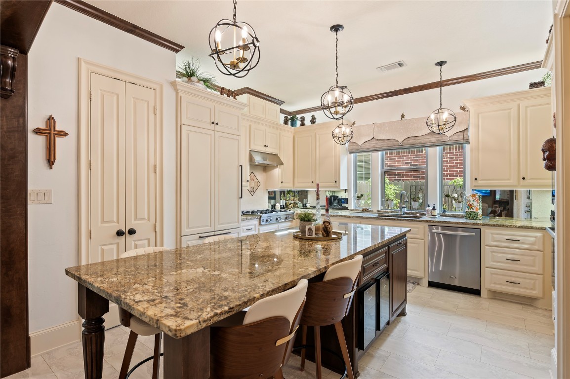 2201 Water Way Seabrook, TX 77586 - Photo 25 of 48 This kitchen features elegant cabinetry and a large granite island with seating. It includes modern stainless steel appliances, pendant lighting, and a spacious double-door pantry. Large windows offer natural light and a view of the outdoor area.