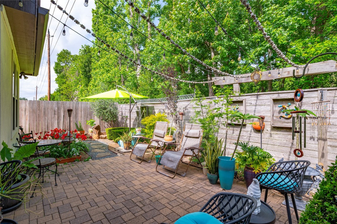 2201 Water Way Seabrook, TX 77586 - Photo 38 of 48 Charming backyard patio with brick flooring, cozy seating, and lush greenery. Features string lights, decorative elements, and vibrant plants for a relaxing outdoor retreat.