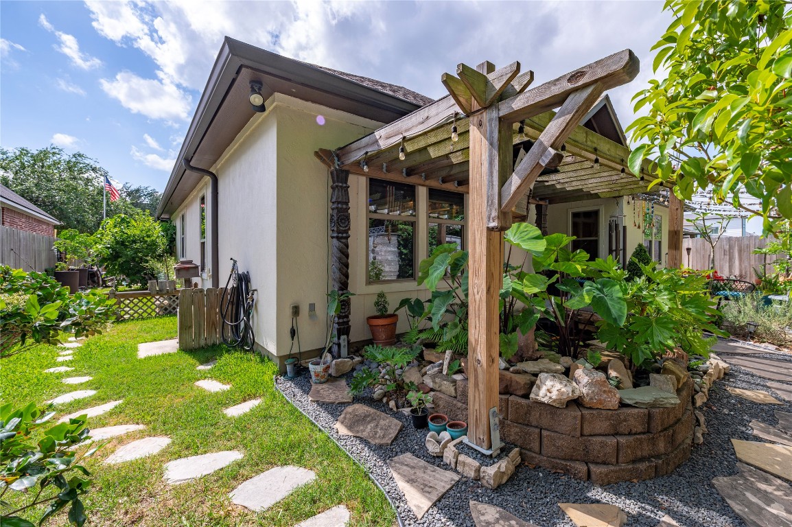 2201 Water Way Seabrook, TX 77586 - Photo 39 of 48 Charming backyard featuring a cozy patio with a wooden pergola adorned with lush plants. The stone pathway leads through a well-maintained garden, offering a peaceful outdoor retreat.
