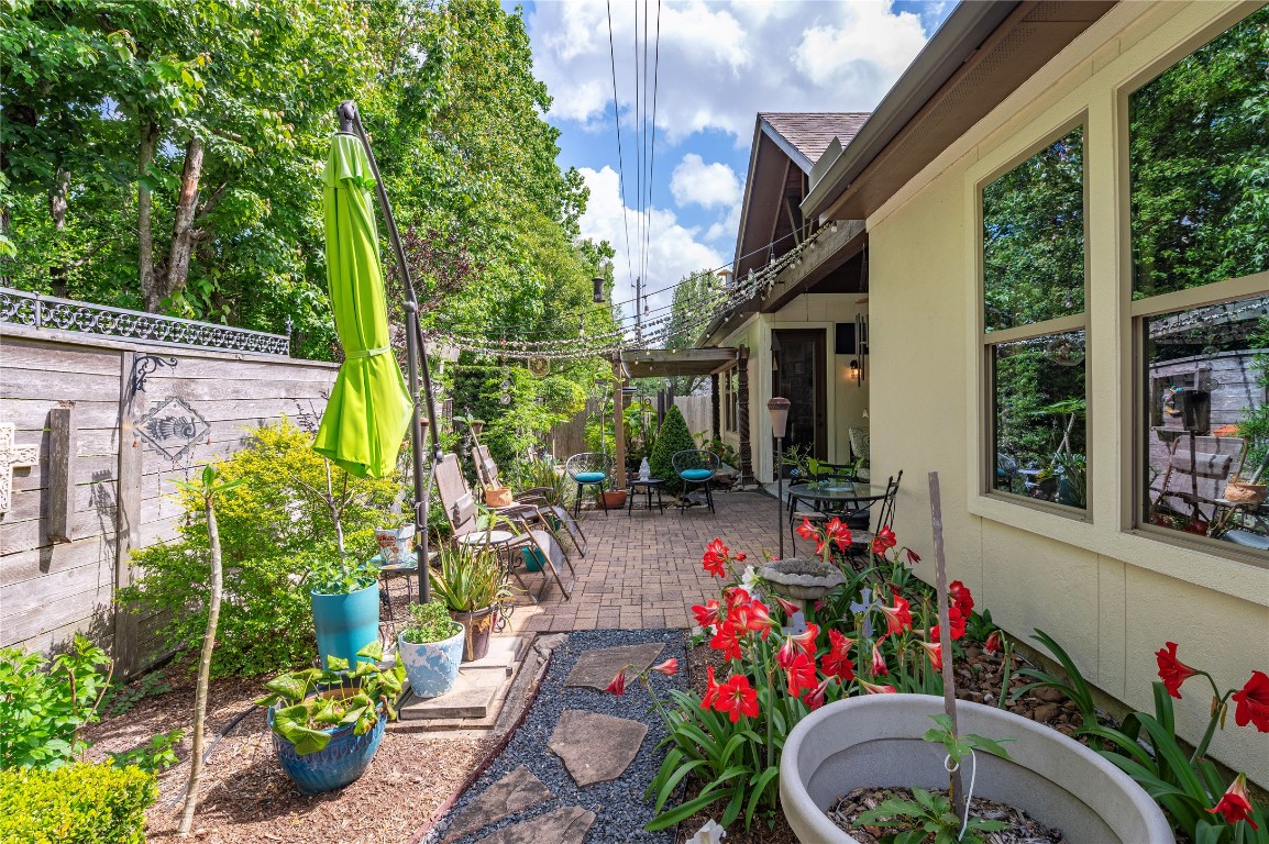 2201 Water Way Seabrook, TX 77586 - Photo 42 of 48 Charming patio area with a cozy, landscaped garden featuring colorful flowers and potted plants. The space is perfect for outdoor relaxation and entertaining, with seating and a pergola for shade. Lush greenery surrounds the area, providing a peaceful retreat.