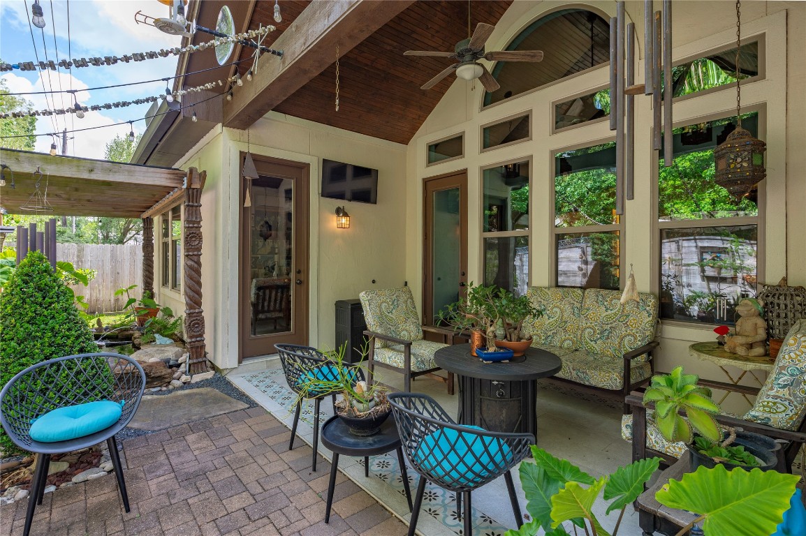 2201 Water Way Seabrook, TX 77586 - Photo 43 of 48 This photo showcases a cozy outdoor patio with comfortable seating, lush greenery, and decorative elements. The space features a ceiling fan, string lights, and a tranquil atmosphere perfect for relaxation.