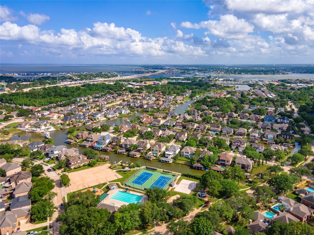 2201 Water Way Seabrook, TX 77586 - Photo 46 of 48 This aerial view showcases a vibrant, waterfront neighborhood with well-maintained homes, lush greenery, and convenient amenities such as tennis courts and a swimming pool. Ideal for families seeking a scenic and active community.