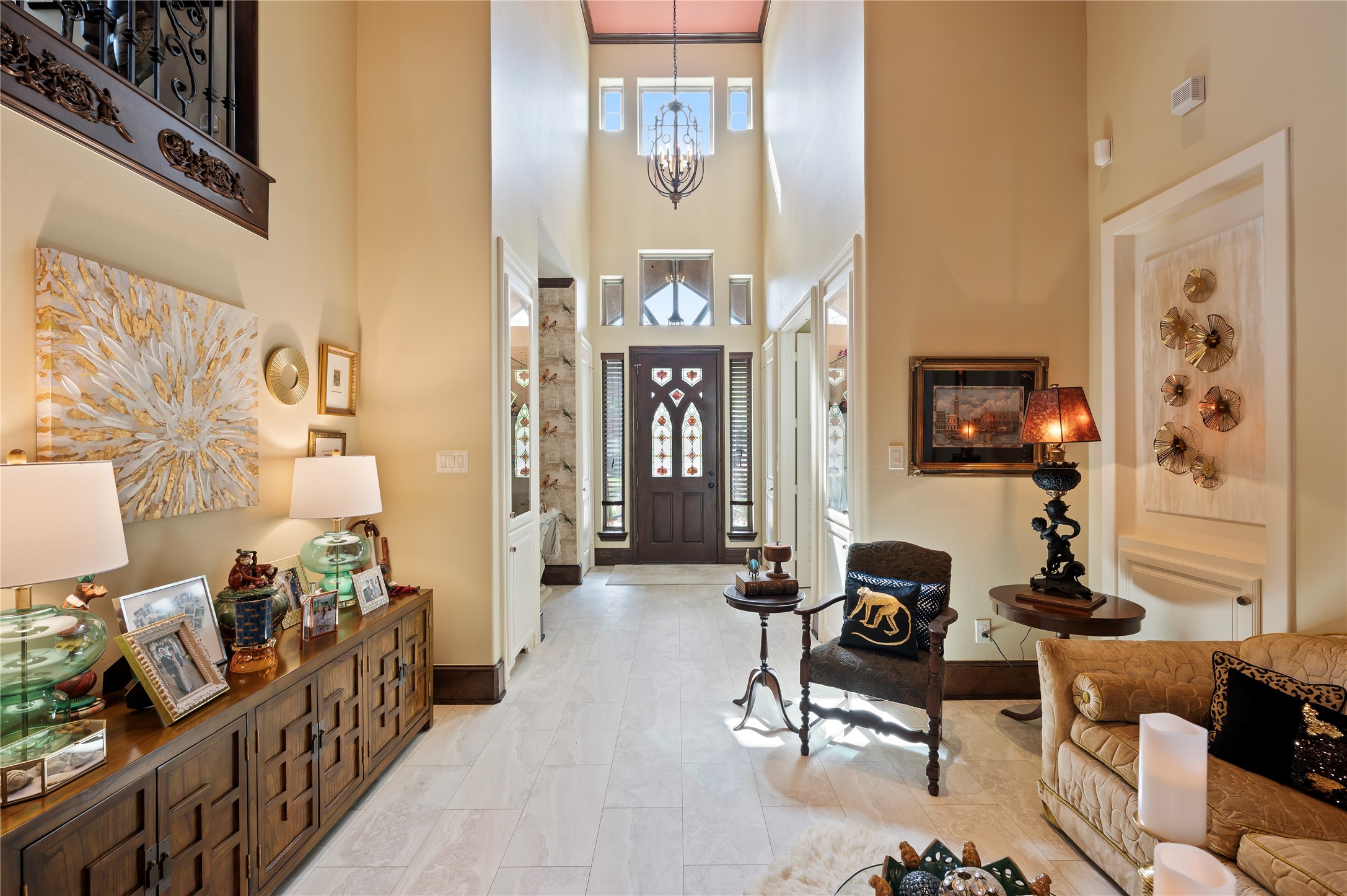 2201 Water Way Seabrook, TX 77586 - Photo 7 of 48 This elegant entryway features high ceilings, a grand chandelier, and a beautifully detailed front door. The space is warmly lit with stylish lamps and adorned with tasteful art and decor, creating a welcoming and sophisticated ambiance.
