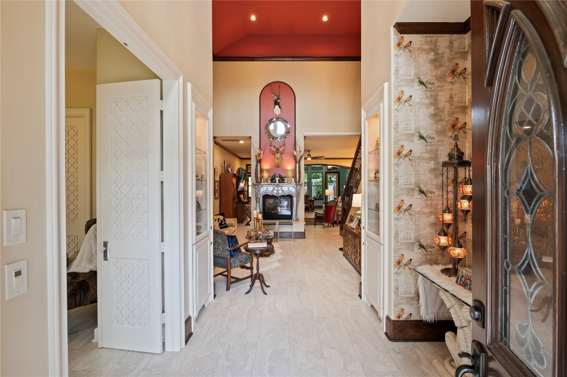 2201 Water Way Seabrook, TX 77586 - Photo 9 of 48 This inviting entryway features elegant double doors to the guest suite, stylish wallpaper, and a glimpse into a cozy living area with a 2-sided fireplace. High ceilings and warm lighting enhance the welcoming ambiance.