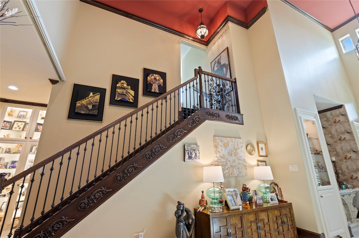 2201 Water Way Seabrook, TX 77586 - Photo 10 of 48 This photo showcases a stylish, open staircase with ornate iron railings and decorative wood trim. The high ceiling adds to the spacious feel, with a warm, inviting color scheme and wall art enhancing the elegance. A cozy corner with a sideboard and tasteful decor completes the sophisticated look.