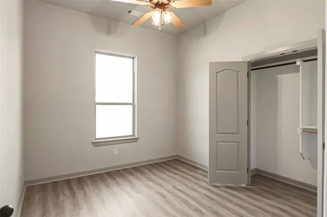 an empty room with windows and chandelier fan